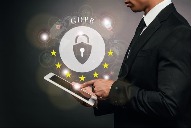 A businessman holding a tablet beside a GDPR padlock encircled by EU stars.